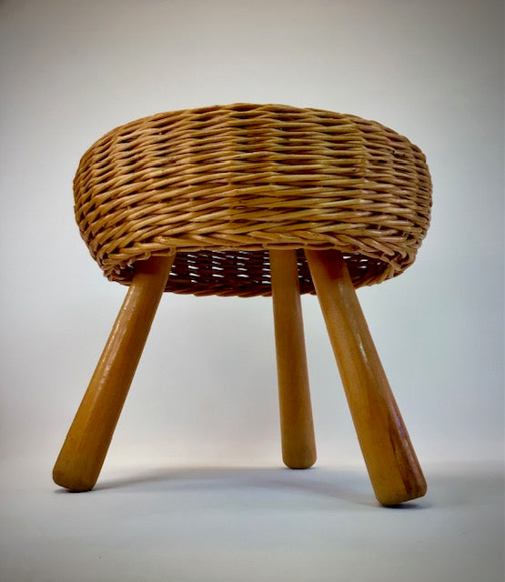 Wicker stool with wooden legs on a plain background