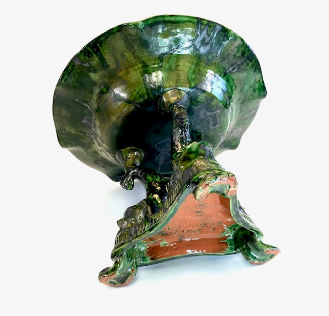 Decorative green shell with a small figure inside on a white background