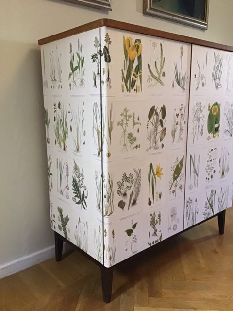 Table with a botanical patterned cover on a wooden floor.