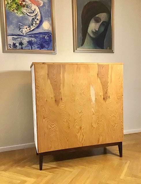 Wooden cabinet with abstract paintings on the wall above it