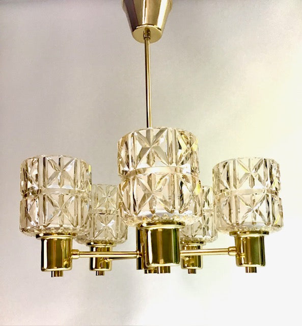 Gold chandelier with clear glass shades on a light gray background