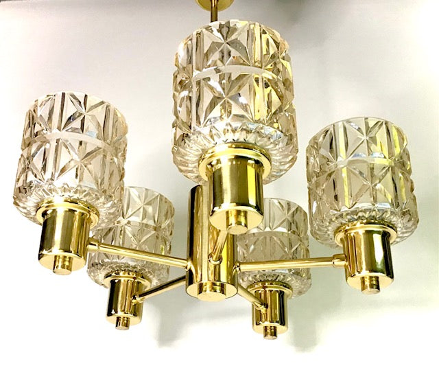 Gold chandelier with crystal-like glass shades on a white background