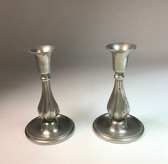 Two silver candle holders on a light gray background