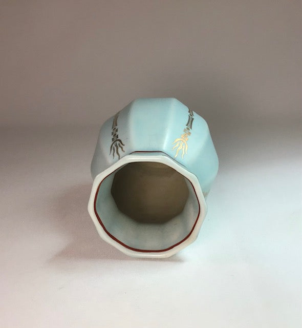 Light blue ceramic vase with decorative patterns on a plain background