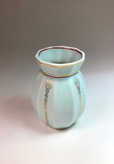 Ceramic vase with gold accents on a neutral background