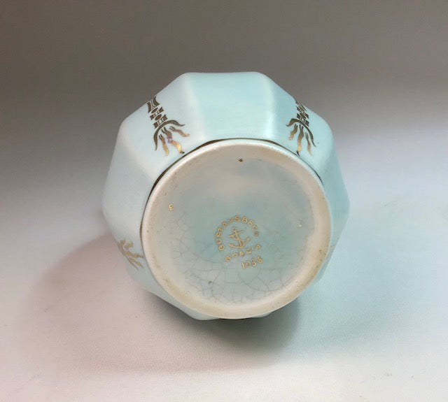 Light blue ceramic container with gold designs on a white background