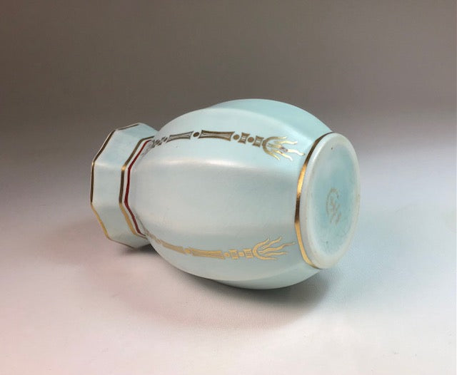 Light blue ceramic vase with gold decorative elements on a gradient background