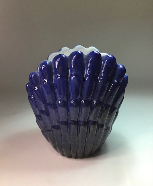Blue glass vase with textured surface on a gradient background