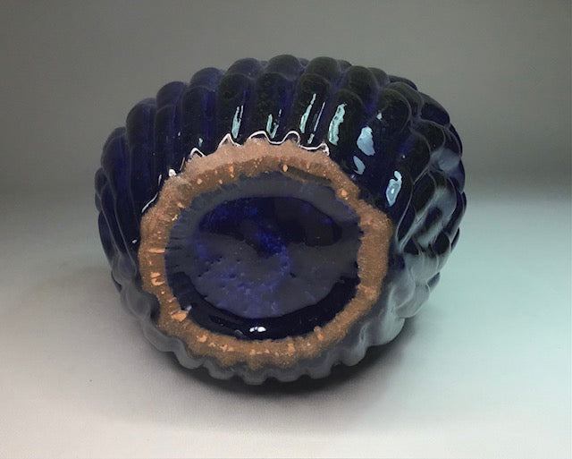 Blue glass bowl with textured surface on a white background