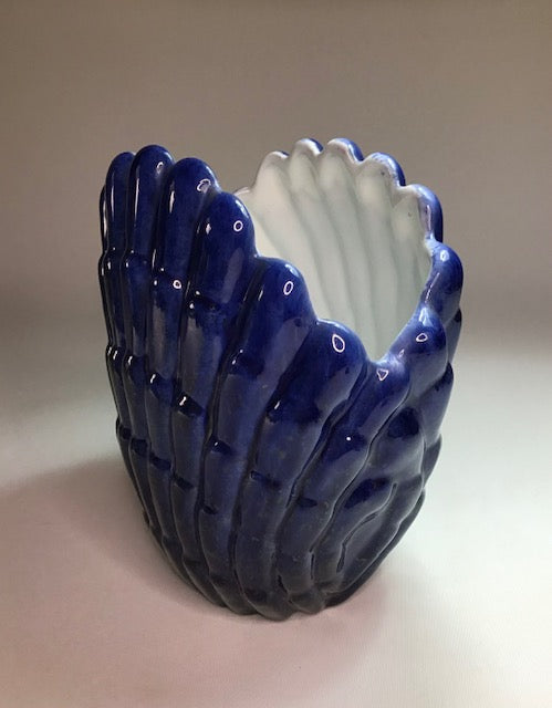 Blue ceramic shell-shaped vase on a beige background