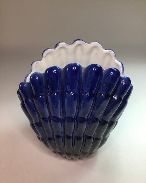 Ceramic shell-shaped bowl with blue interior and white exterior on a neutral background