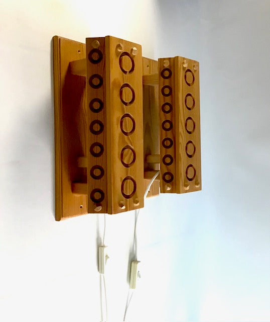 Wooden wall-mounted lamp with circular patterns on a white background