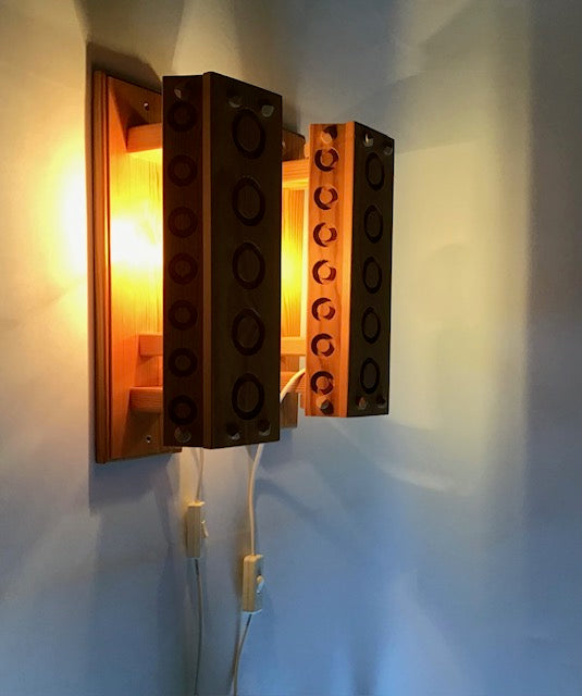 Wall-mounted light fixture designed like interlocking bricks on a white wall.