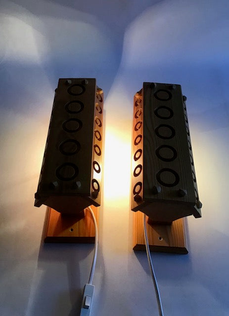 Two wall-mounted light fixtures with a warm glow on a white wall.