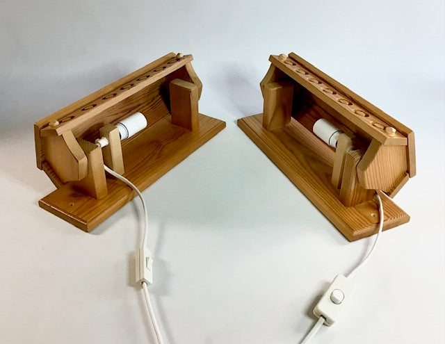 Two wooden wall sockets with white plugs on a light gray background
