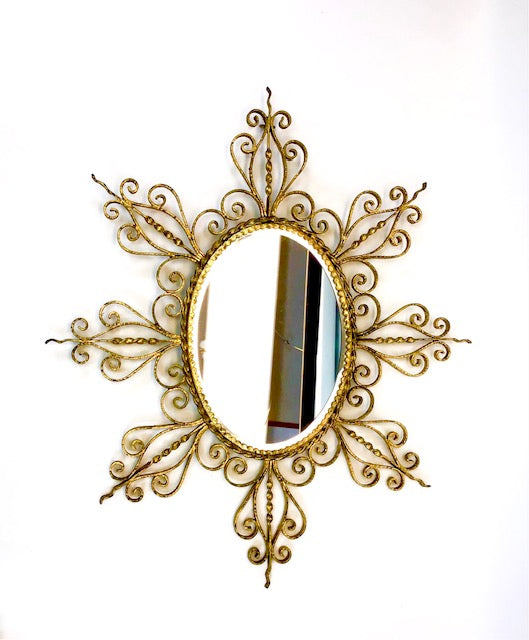 Decorative gold mirror with intricate patterns on a white background