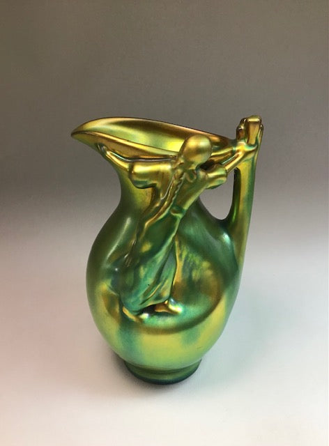 Iridescent green and gold pitcher on a gradient background
