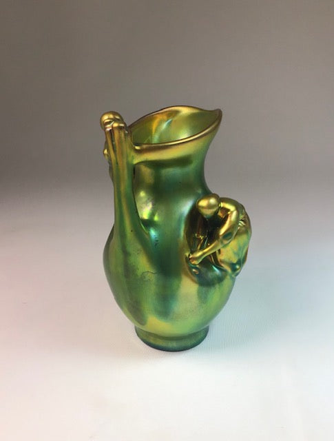 Green and gold ceramic pitcher on a gradient background
