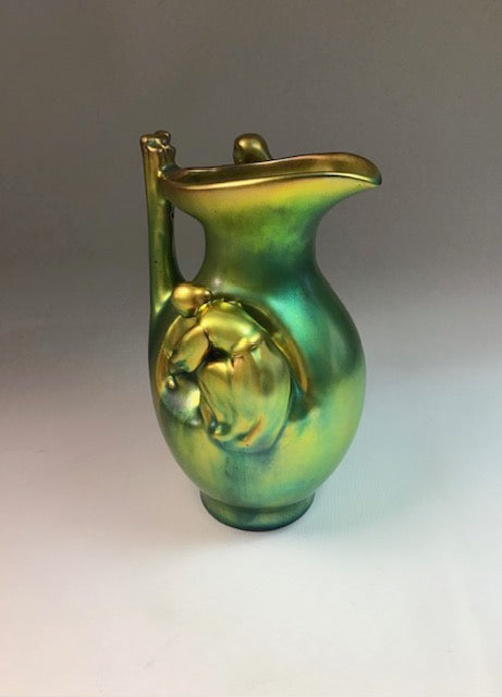 Green and gold ceramic pitcher on a gradient background