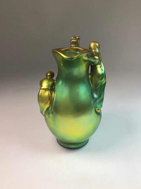 Green and gold ceramic pitcher on a gradient background