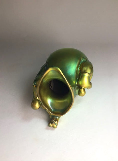 Green and gold decorative object on a plain background