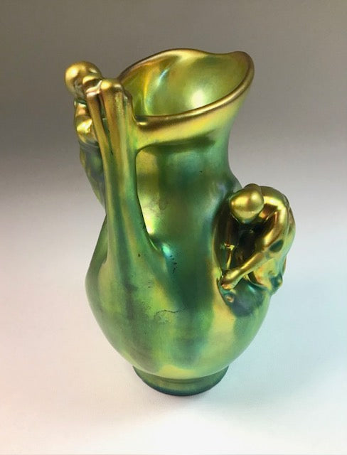 Green and gold ceramic pitcher on a gradient background